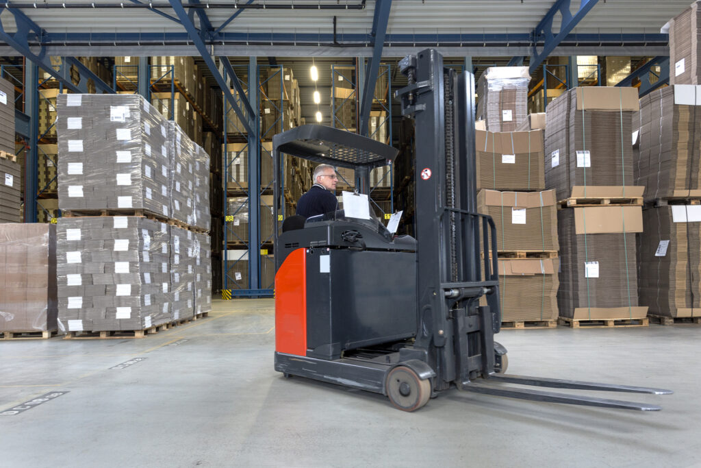 A reach truck parked in the middle of a warehouse.